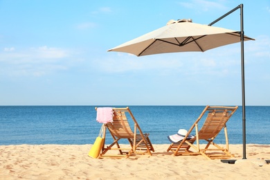 Photo of Empty wooden sunbeds and beach accessories on sandy shore