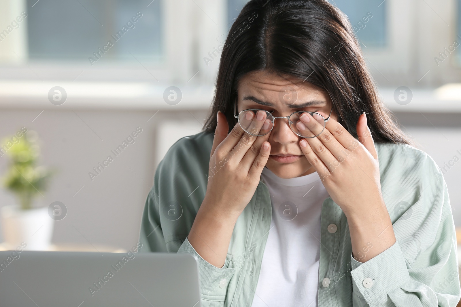 Photo of Young woman suffering from eyestrain in office