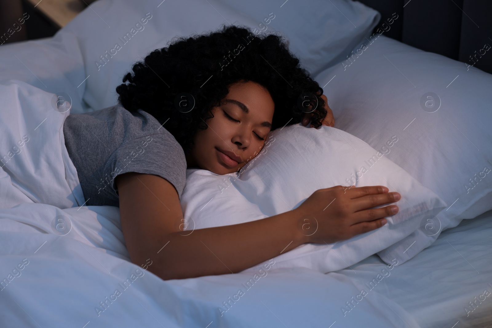 Photo of Young woman sleeping in soft bed at night