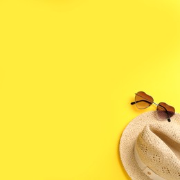 Photo of Hat and sunglasses on yellow background, flat lay with space for text. Sun protection accessories