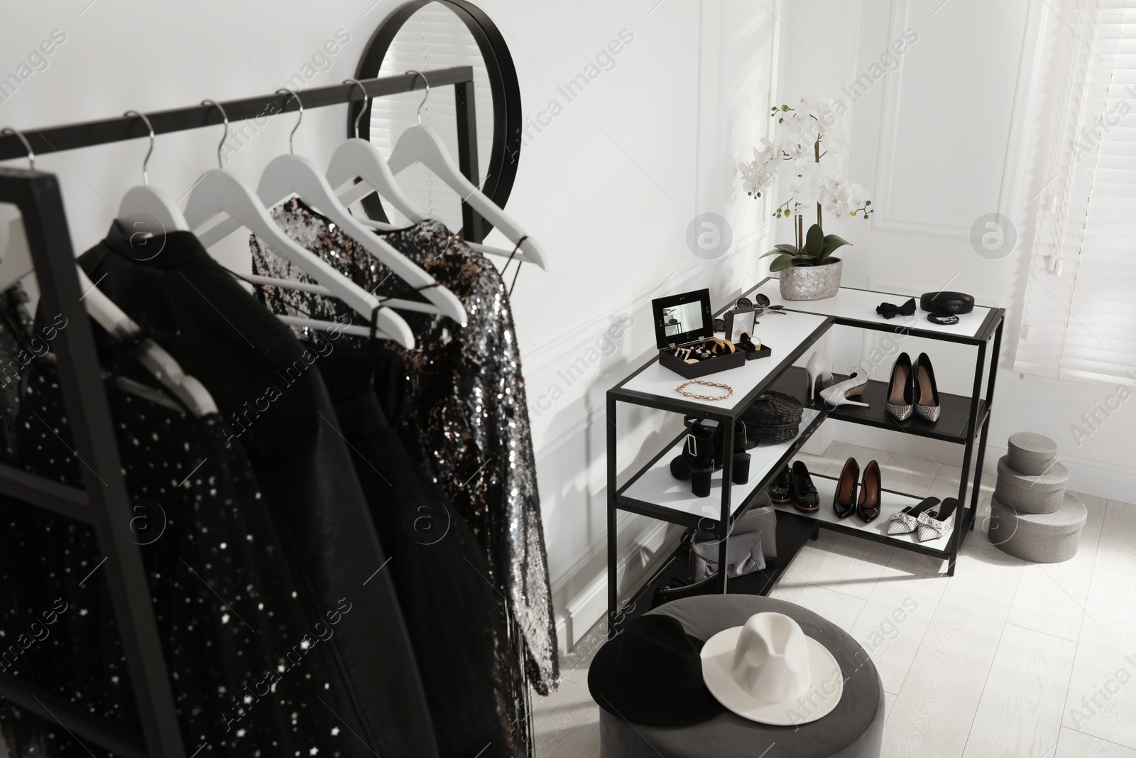 Photo of Shelving unit with stylish women's shoes, clothes and accessories in dressing room