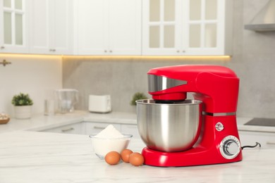 Photo of Modern red stand mixer, eggs and bowl with flour on white marble table in kitchen, space for text