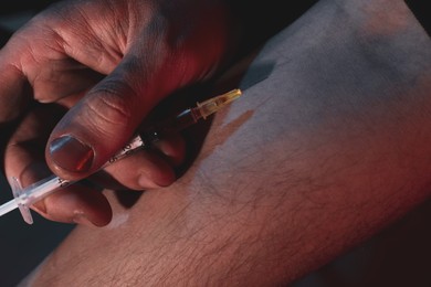 Man taking drugs on dark background, closeup