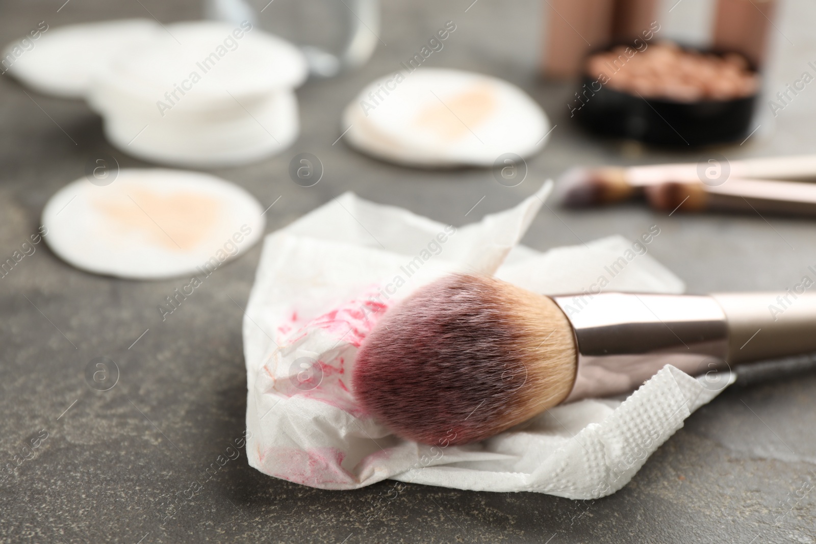 Photo of Dirty tissue and brush on grey table, closeup