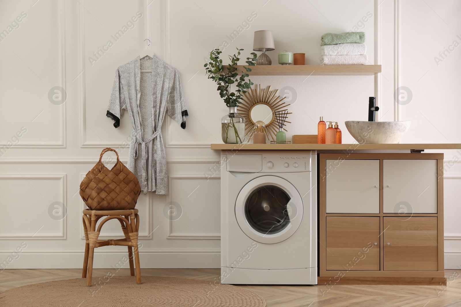 Photo of Laundry room interior with modern washing machine and stylish vessel sink on countertop