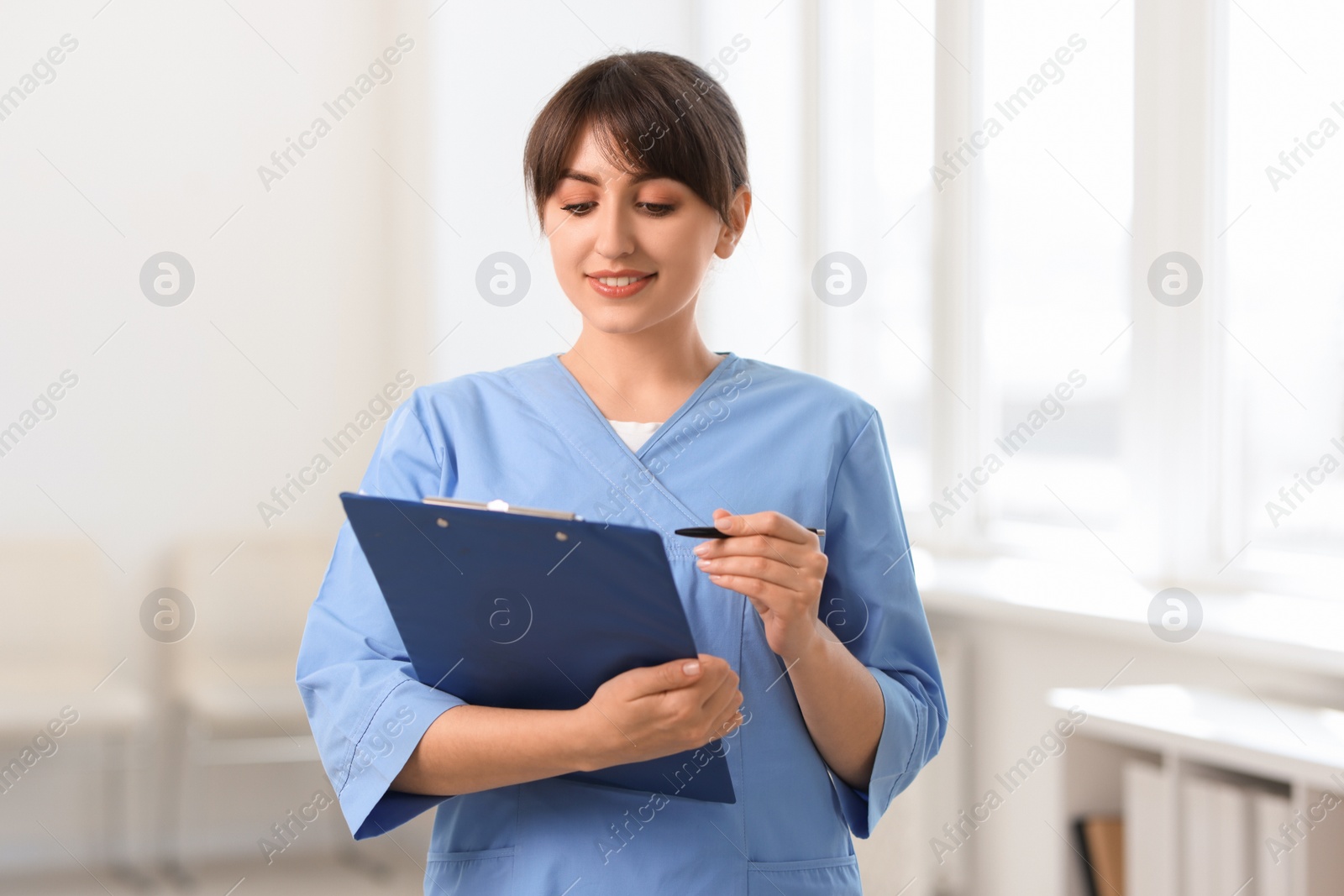 Photo of Portrait of smiling medical assistant with clipboard and pen in hospital