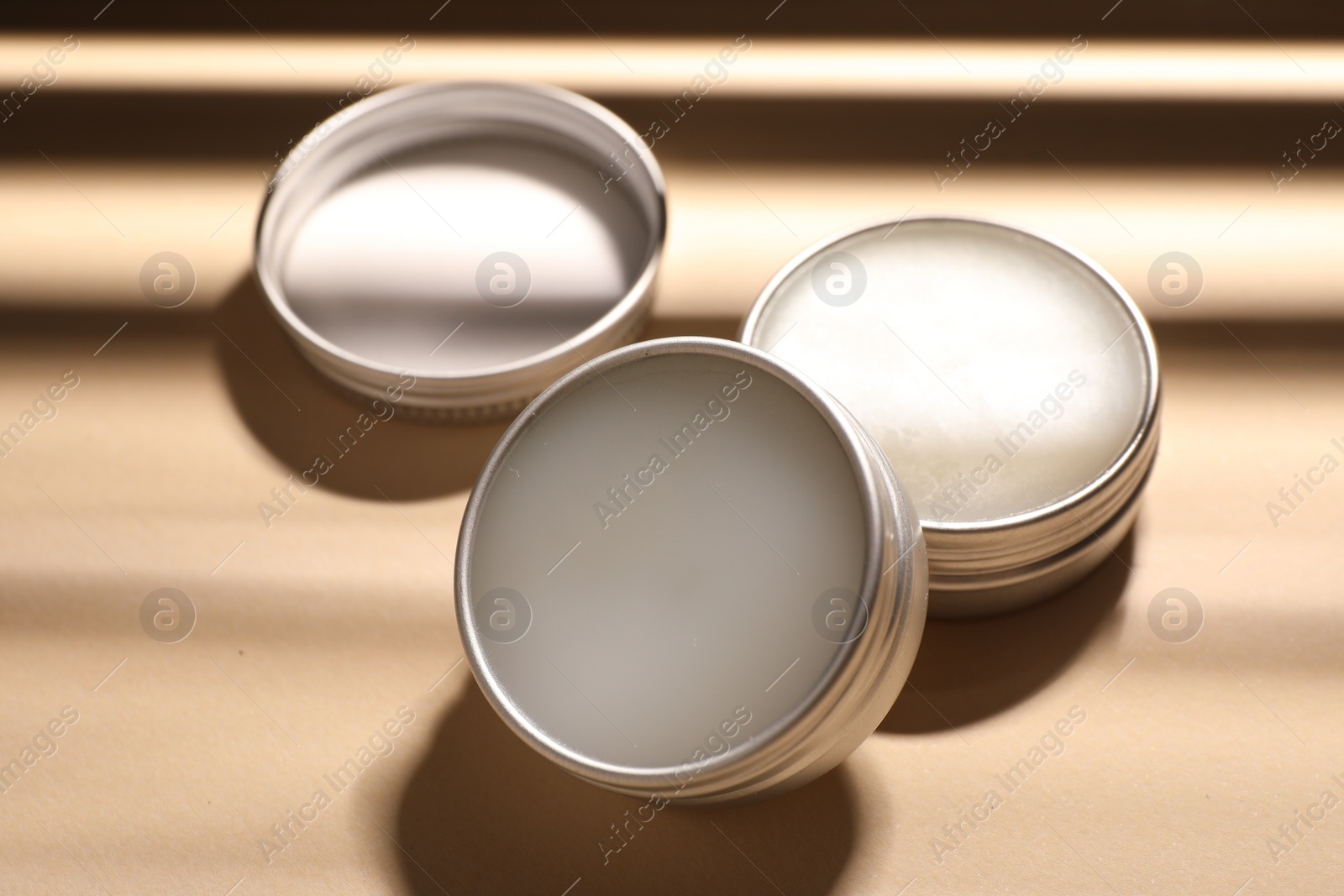 Photo of Lip balms on beige background, closeup view
