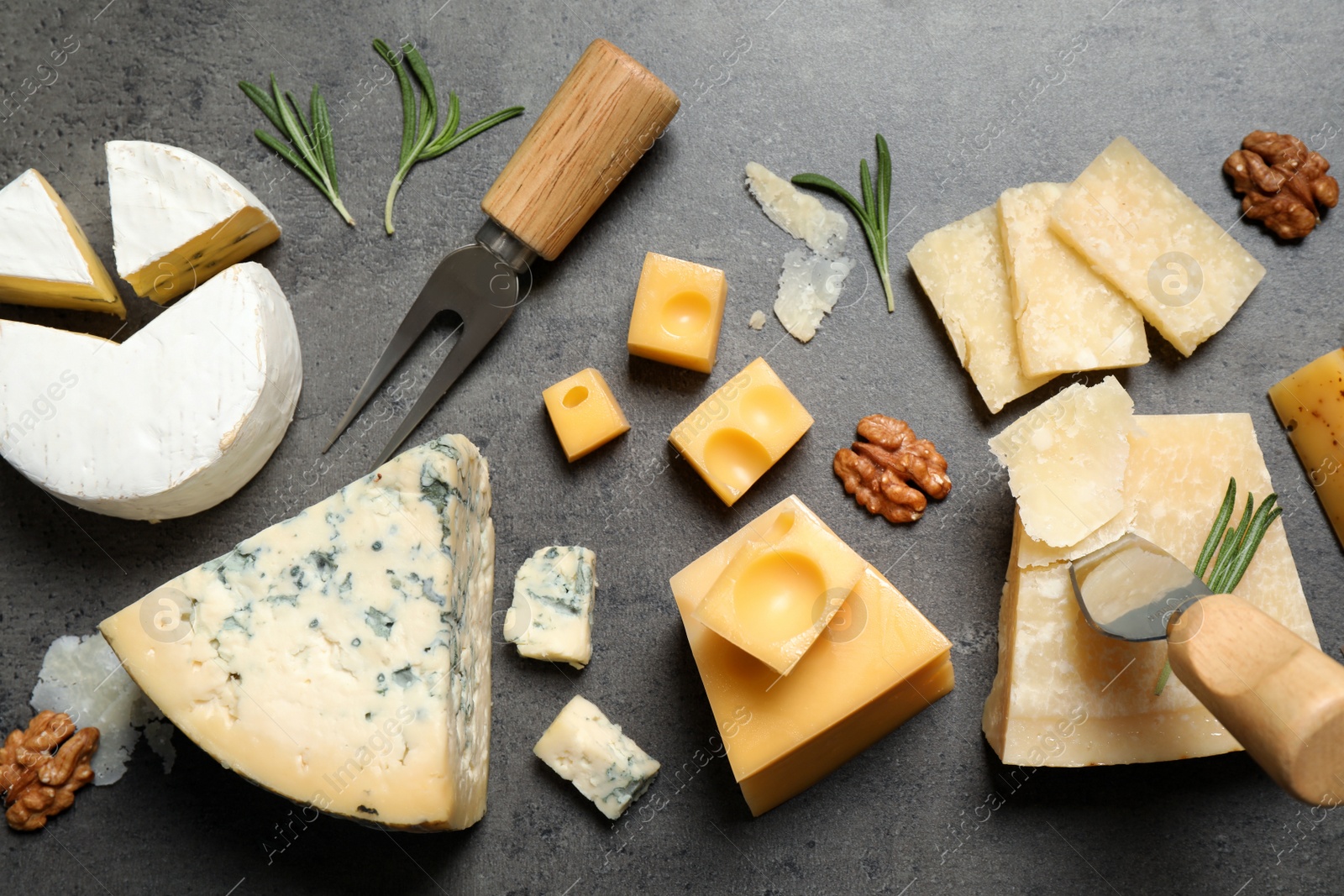 Photo of Flat lay composition with different sorts of cheese and knives on grey table