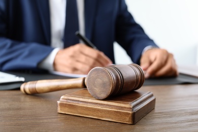 Photo of Wooden gavel and blurred lawyer on background. Notary services