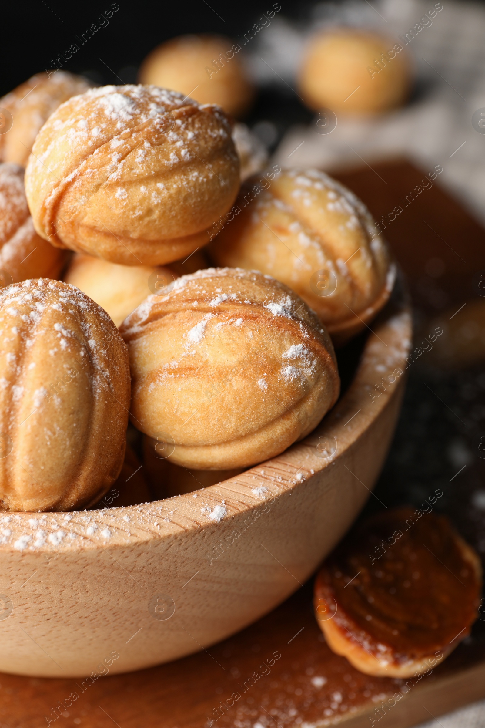 Photo of Delicious nut shaped cookies with powdered sugar on wooden table, closeup