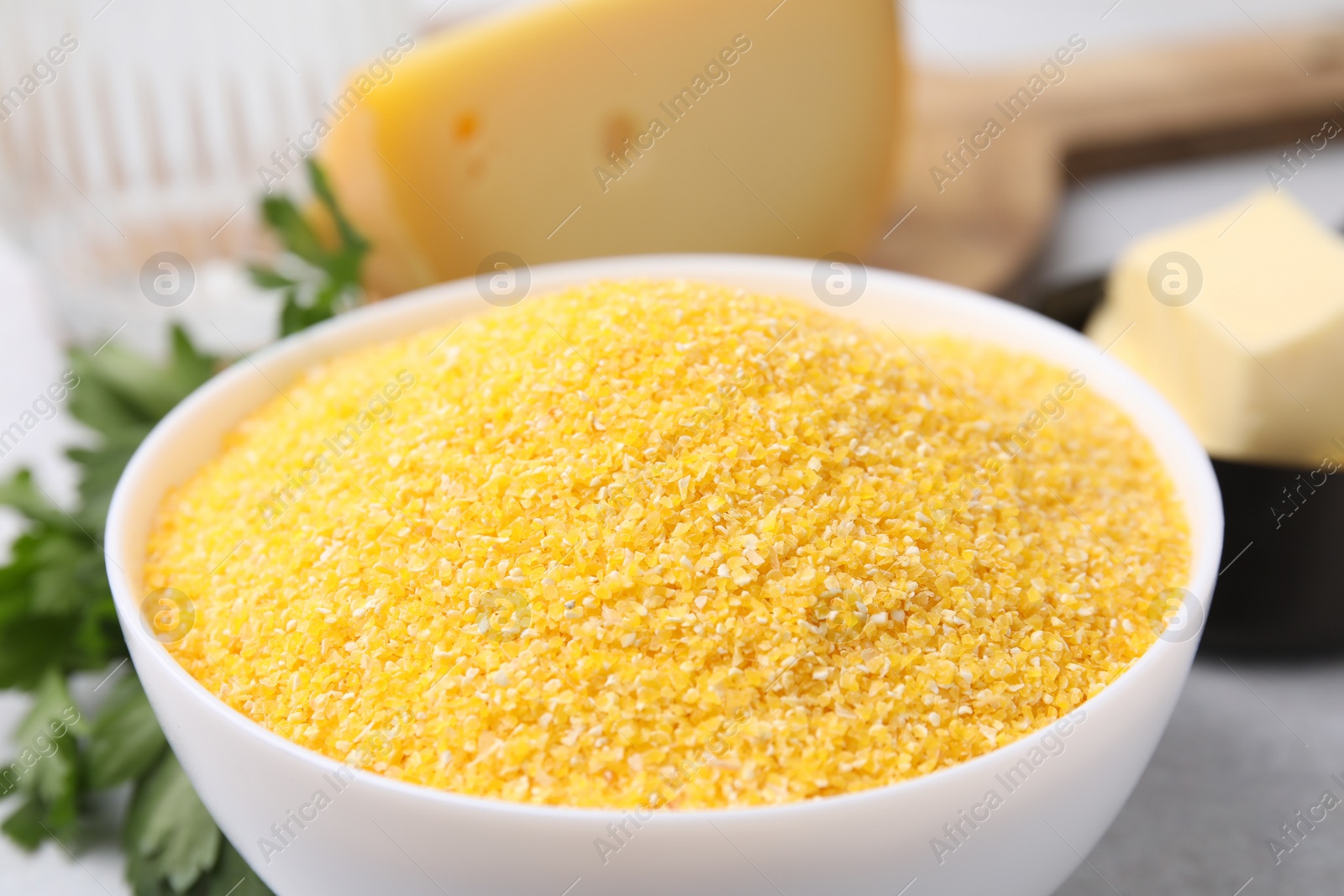 Photo of Raw cornmeal in bowl on table, closeup