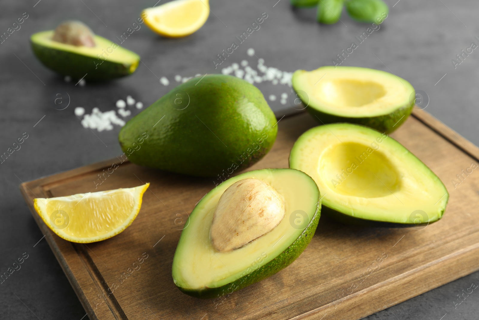 Photo of Wooden board with ripe avocados and lemon on table