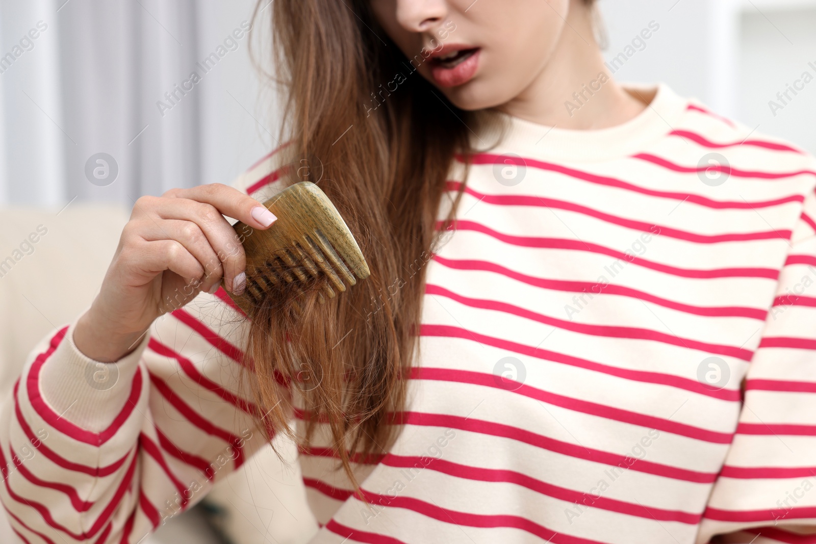 Photo of Upset woman brushing her hair indoors, closeup. Alopecia problem