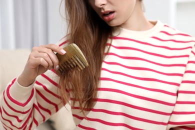 Upset woman brushing her hair indoors, closeup. Alopecia problem