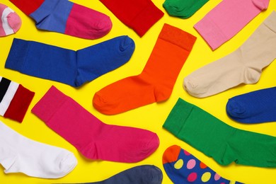 Photo of Different colorful socks on yellow background, flat lay