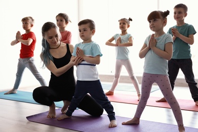 Photo of Little children and their teacher practicing yoga in gym