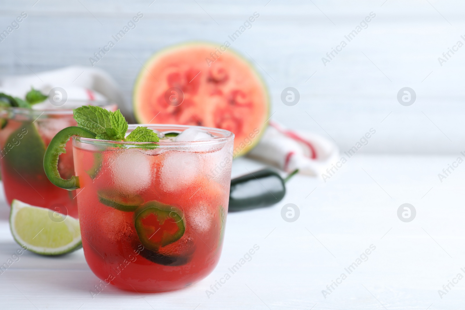 Photo of Spicy cocktail with jalapeno and mint on white table. Space for text