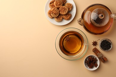 Photo of Flat lay composition with aromatic tea, cookies and anise stars on beige table. Space for text