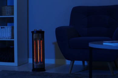 Electric infrared heater in dark living room at night