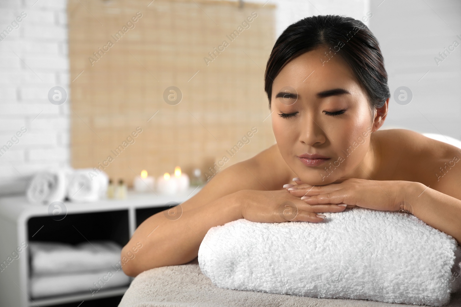 Photo of Beautiful Asian woman lying on massage table in spa salon. Space for text