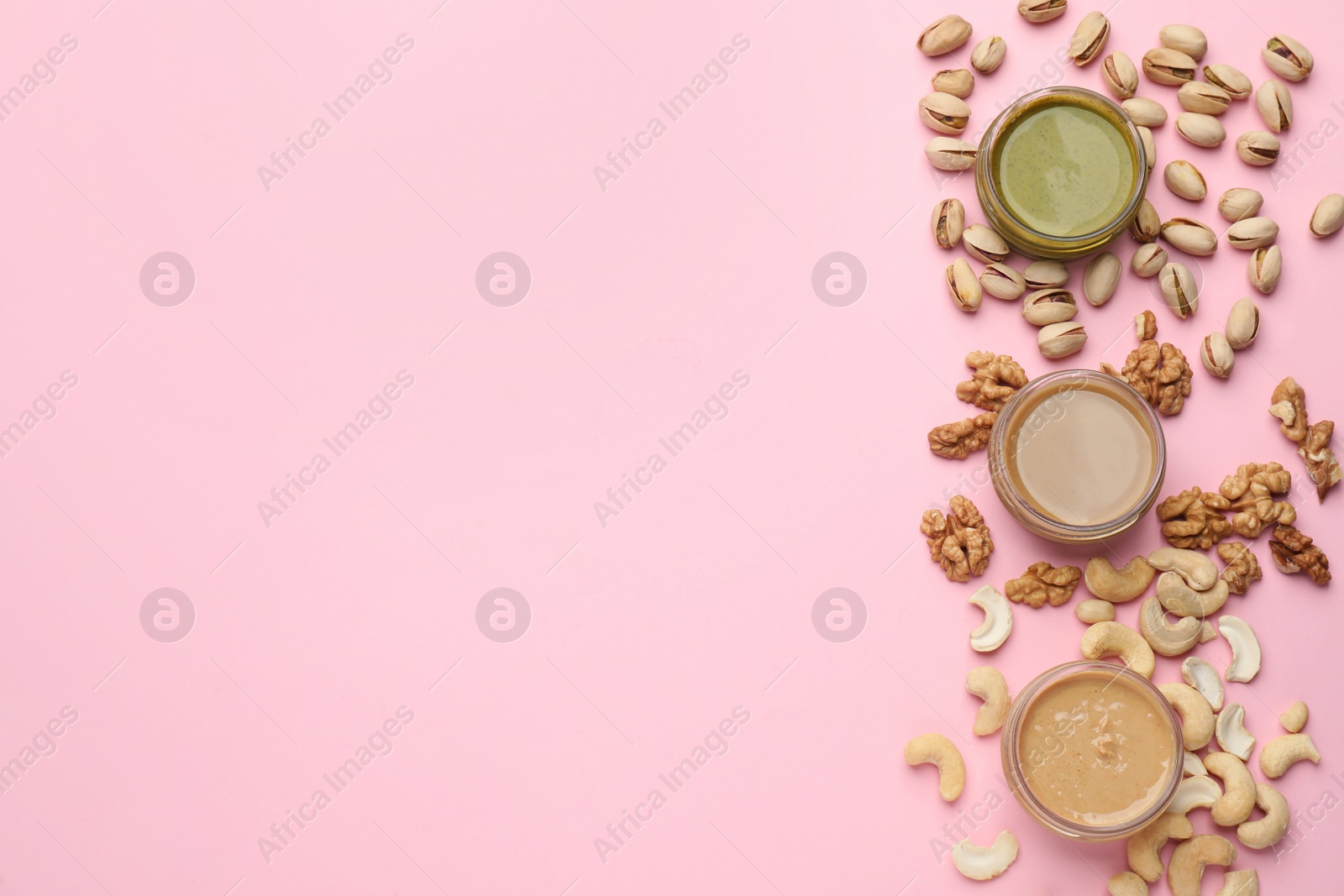Photo of Different types of delicious nut butters and ingredients on pink background, flat lay. Space for text
