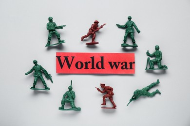 Photo of Paper with words World War and toy soldiers on white background, flat lay