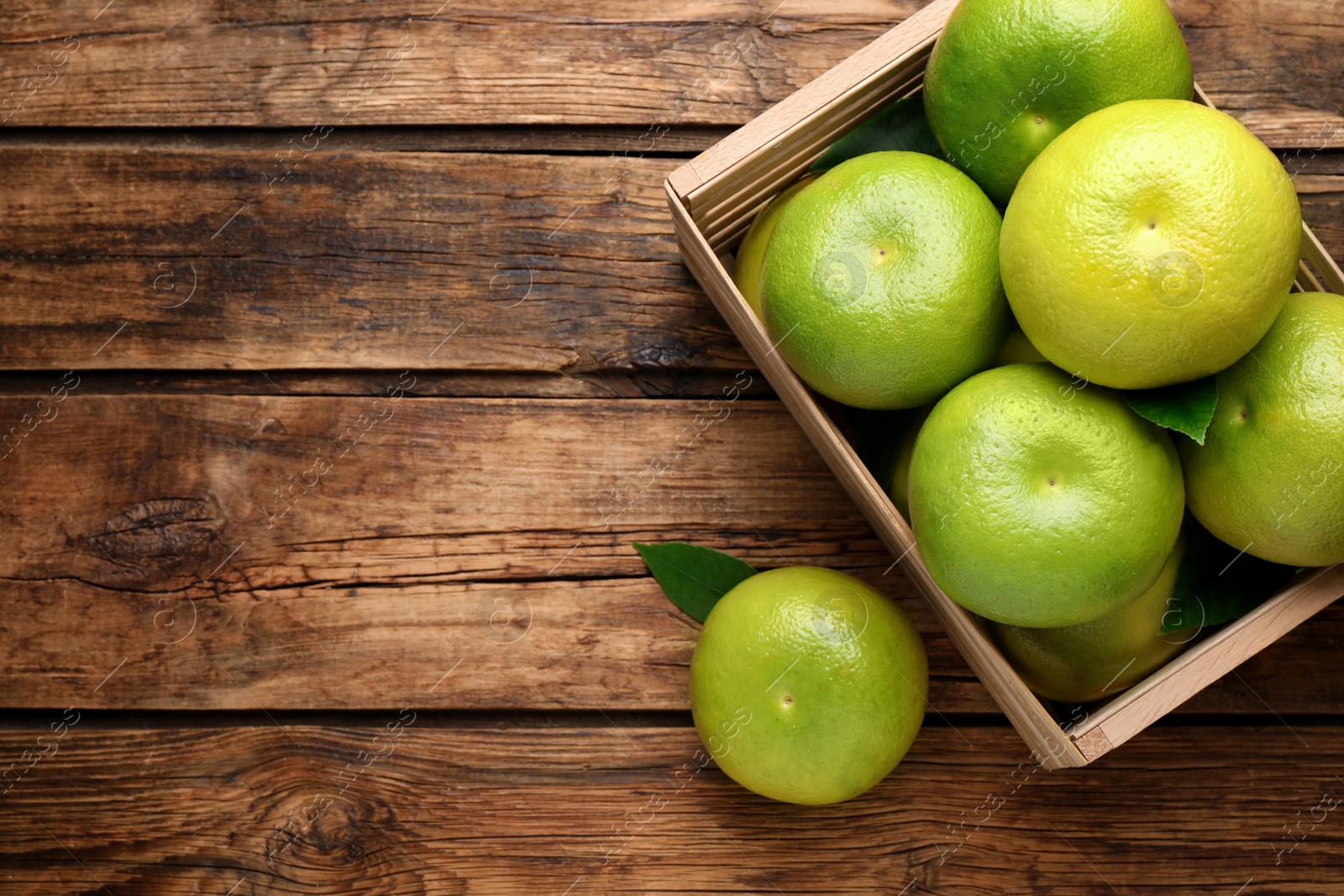 Photo of Fresh ripe sweetie fruits in crate on wooden table, flat lay. Space for text