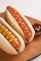 Photo of Tasty hot dogs with ketchup and mustard on white table, closeup