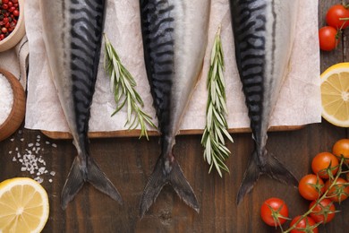 Photo of Raw mackerel, tomatoes and rosemary on wooden table, flat lay