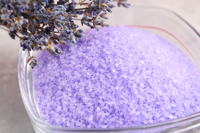 Photo of Violet sea salt in bowl and lavender flowers on table, closeup