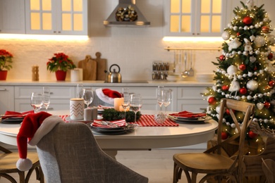 Photo of Table with dishware in beautiful kitchen interior decorated for Christmas