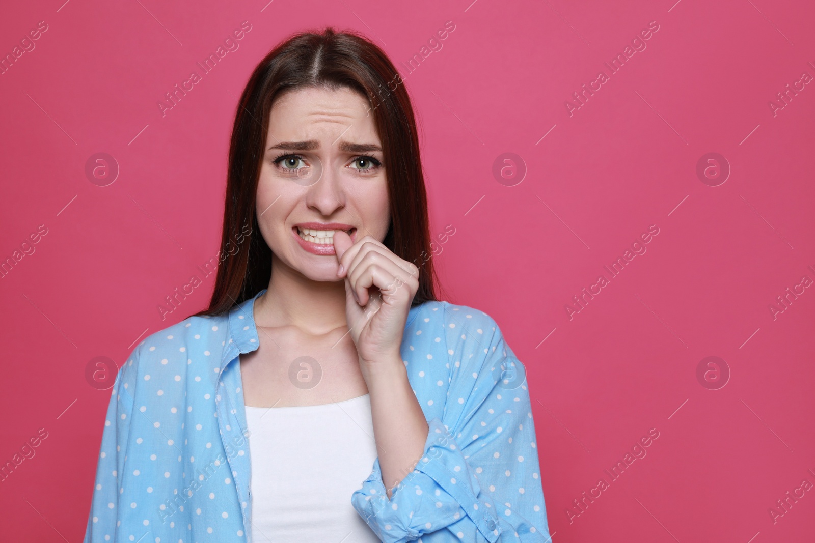 Photo of Young woman biting her nails on pink background. Space for text