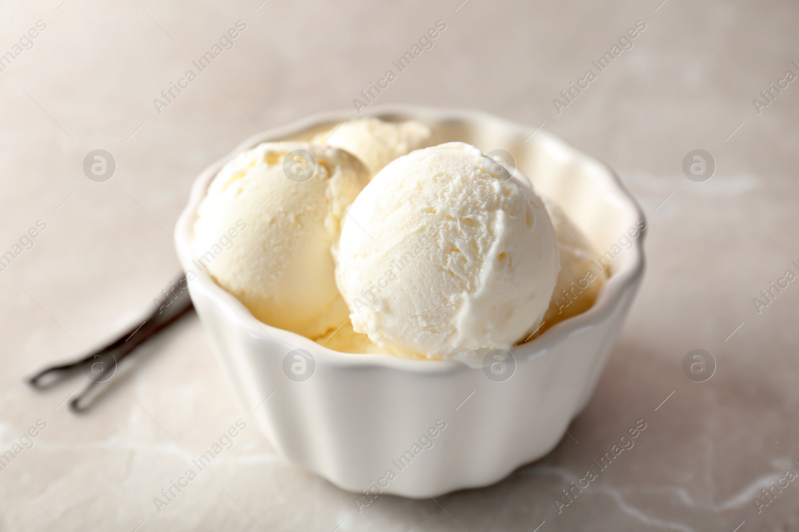 Photo of Bowl with tasty vanilla ice cream on light background