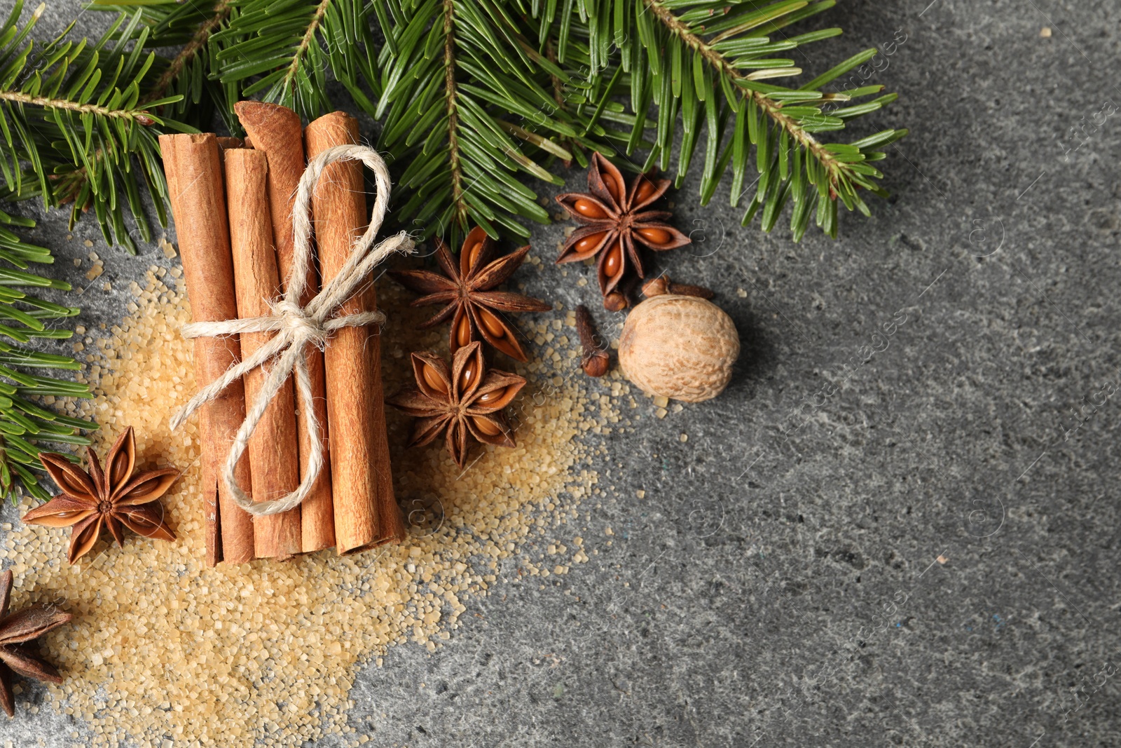 Photo of Different spices and fir branches on gray table, flat lay. Space for text