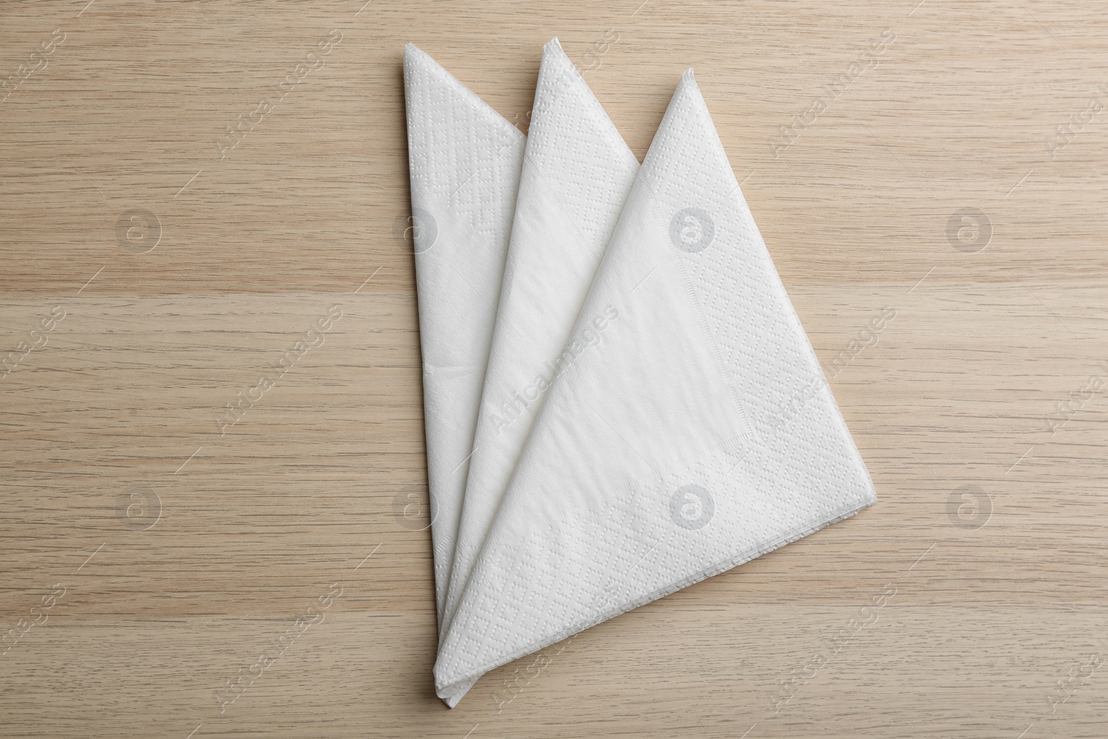 Photo of Folded white clean paper tissues on wooden table, flat lay