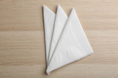 Photo of Folded white clean paper tissues on wooden table, flat lay