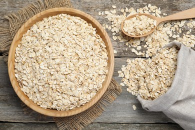 Photo of Oatmeal, bowl, spoon and bag on wooden table, flat lay