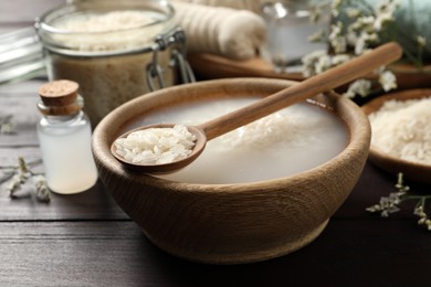 Photo of Bowl with soaked rice and spoon on wooden table, closeup