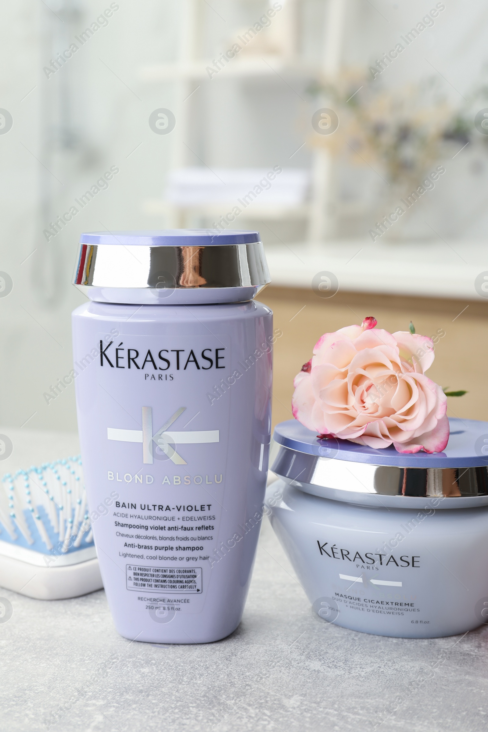 Photo of MYKOLAIV, UKRAINE - SEPTEMBER 07, 2021: Kerastase hair care cosmetic products and brush on light table in bathroom