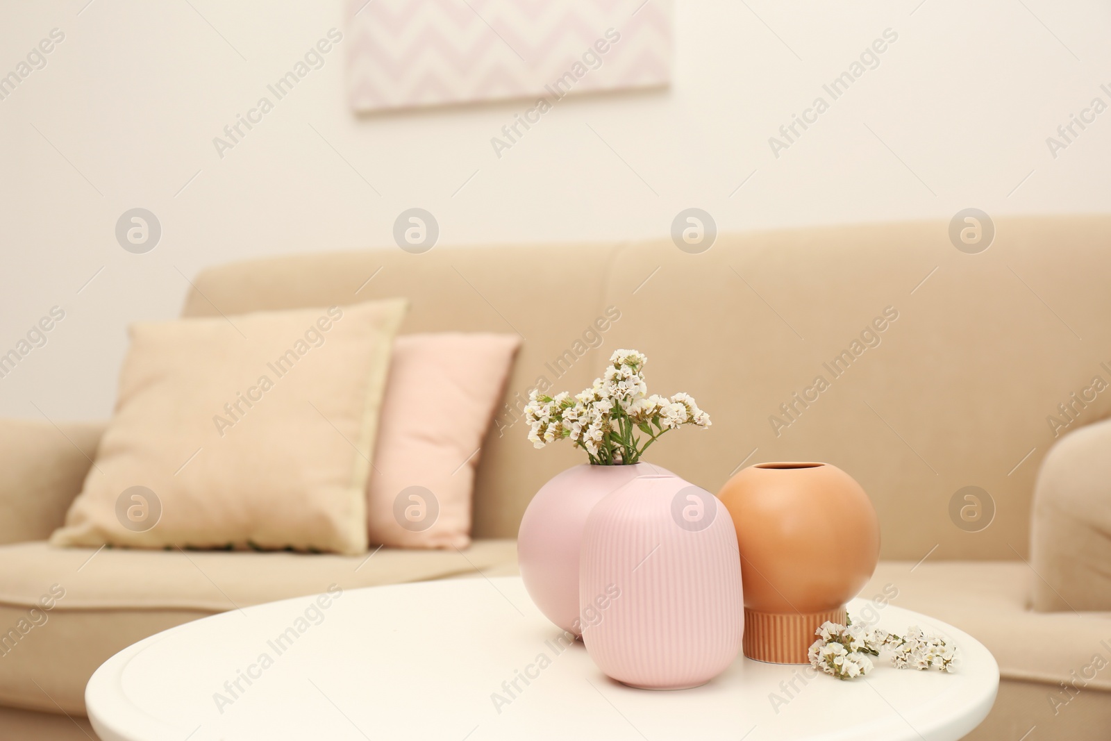 Photo of Beautiful ceramic vases and flowers on table in living room