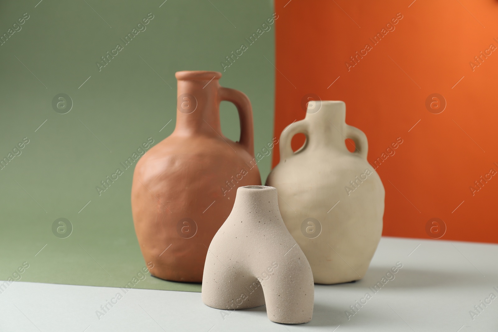 Photo of Clay flagons and vase on color background