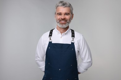 Photo of Happy man wearing kitchen apron on grey background. Mockup for design
