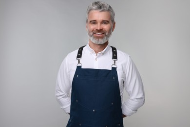 Happy man wearing kitchen apron on grey background. Mockup for design