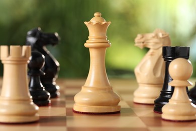 Different game pieces on chessboard against blurred background, closeup