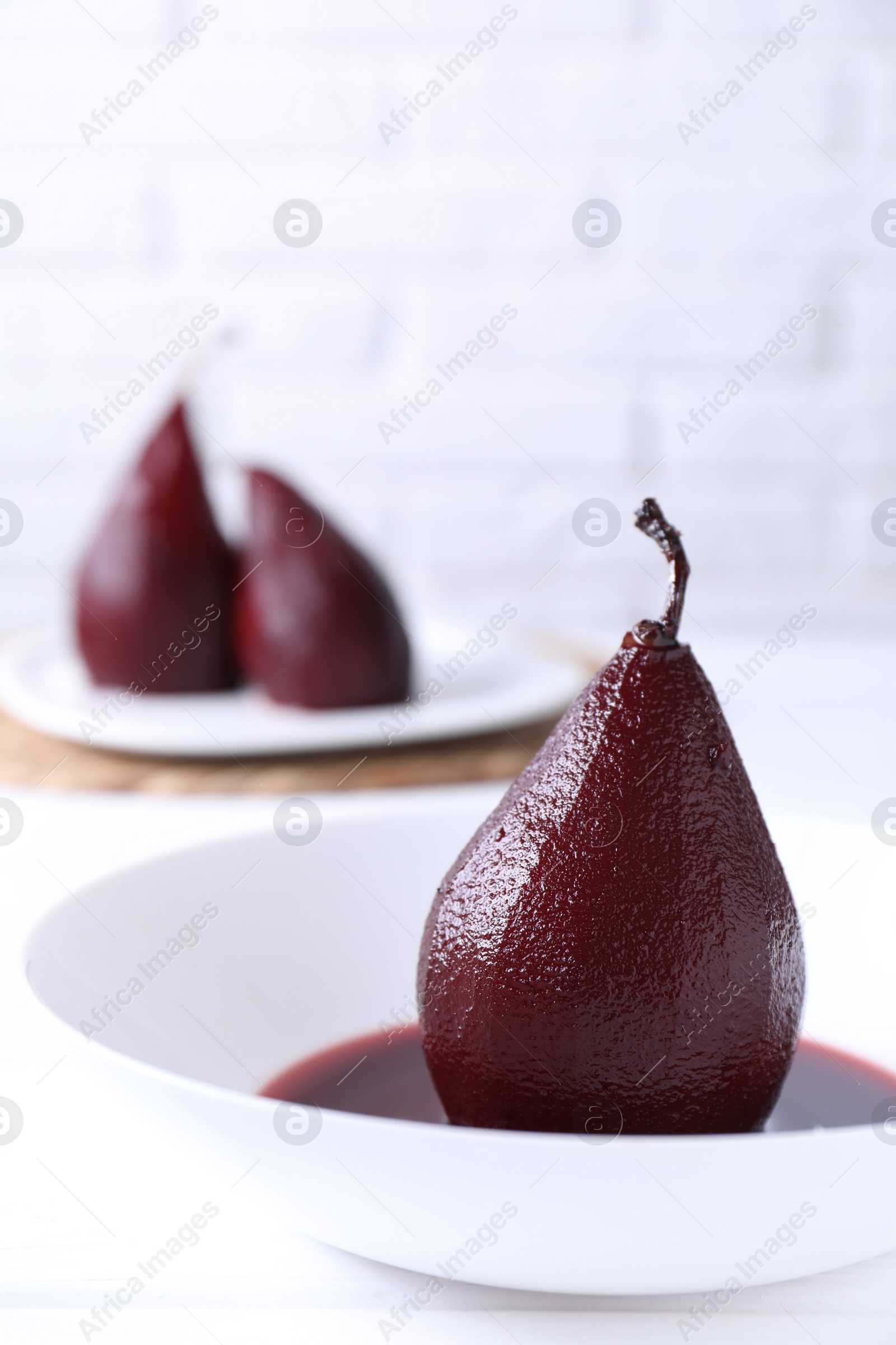 Photo of Tasty red wine poached pear on white wooden table, closeup