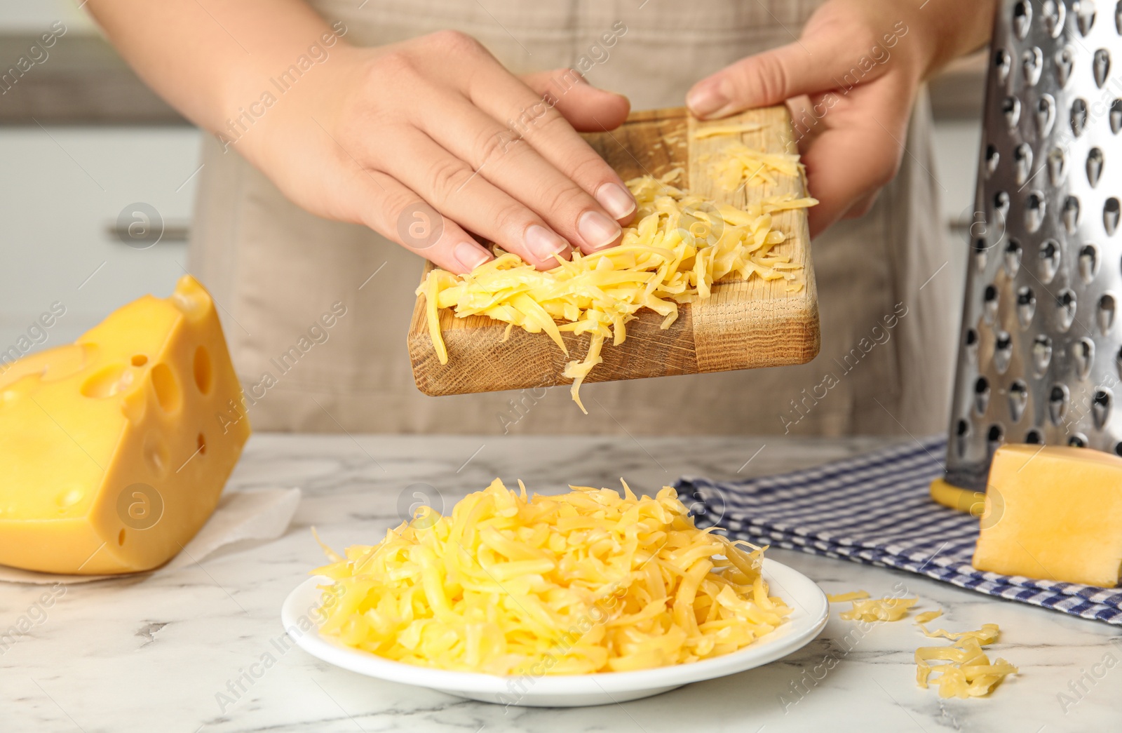 Photo of Woman with grated cheese at kitchen table, closeup