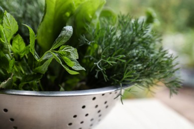 Photo of Different herbs in colander on white table outdoors, closeup