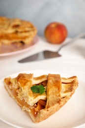 Photo of Piece of delicious fresh peach pie served on white table, closeup