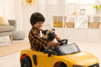 Little boy with his dog in toy car at home