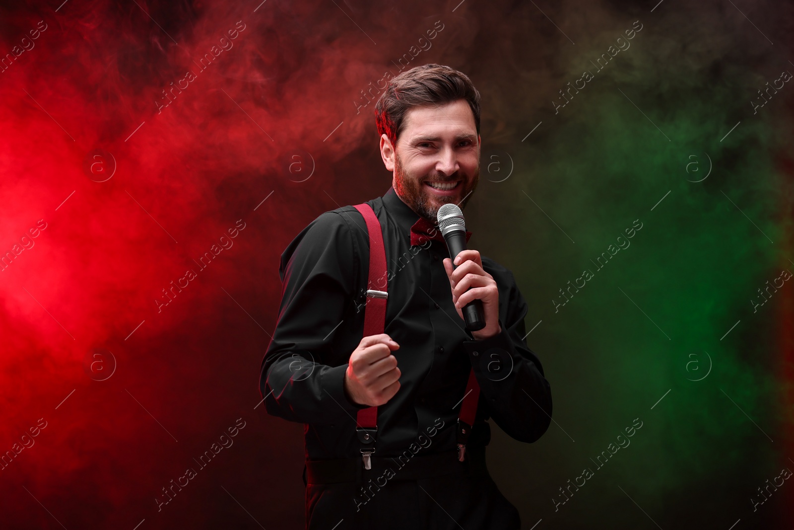 Photo of Emotional man with microphone singing in color lights